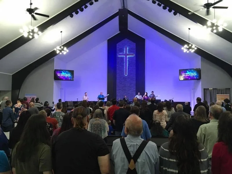 The Cross Point congregation gathering for worship beneath the sanctuary’s cross and dark wooden beams.